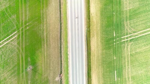 Drohnenaufnahme der Landstraße aus der Luft mit von rechts nach links fahrenden Autos in Form von grünen Feldern in L