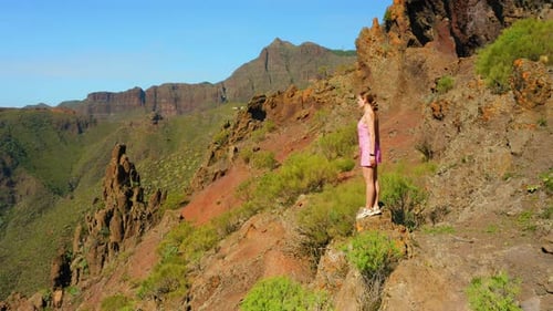 Young Beautiful Woman Enjoys the View of the Gorge From the Top of Mountain Sunset