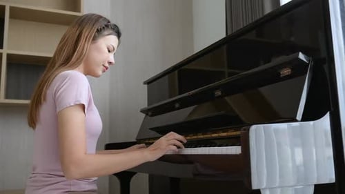 Woman Plays Piano Indoors During Daytime