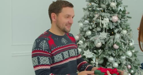 Close-up Young Woman Receiving a Holiday Present From Her Husband. Pretty Girl Hugging with