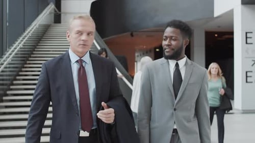 Two Diverse Businessmen Walking through Airport and Talking