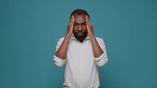 Exhausted Sick Man Suffering From Painful Headache in Studio