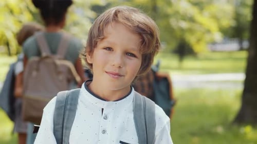 Portrait of Happy Little Schoolboy Smiling at Camera in Park