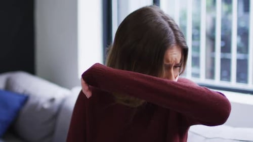Femme portant un masque facial éternuant sur son coude