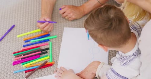 Close Up of a Young Happy Married Couple with Their Son Drawing a Car on a Piece of Paper