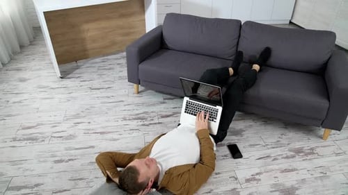 Young Adult Working on Laptop Lying on Floor