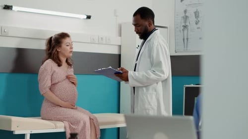Pregnant Woman Talking with Doctor in Clinic