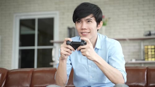 Man Plays Video Game on Couch at Home