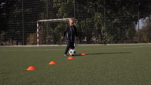 Young Boy Dribbling Soccer Ball on Green Field