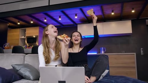 Companheiras se divertindo juntas durante o lazer conjunto, onde comem pizza e assistindo programas
