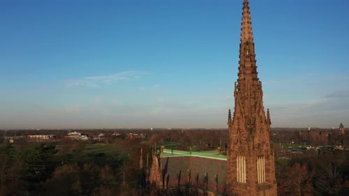 An aerial shot of a beautiful cathedral with a tall steeple, taken at sunrise. The camera dolly in a