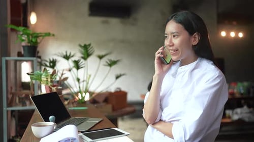 Woman Talking on Phone in Cafe with Laptop