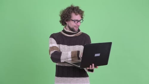 Man Using Laptop Smiling in Front of Green Screen