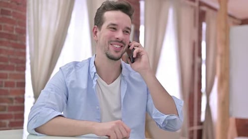 Man Smiles During Phone Call Indoors
