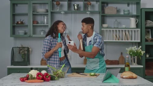Couple Singing Together in Kitchen Using Utensils
