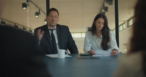 Two business people discuss project ideas with their colleagues in the office meeting room