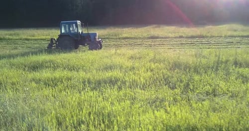 Maschine mit Mäher fährt schnell entlang großer grüner Wiese