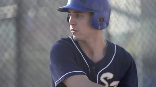 A young man practicing baseball at the batting cages.