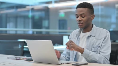 Young Adult Types on Laptop in Modern Office