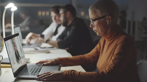 Businesswoman Web Calling on Laptop in Dark Office