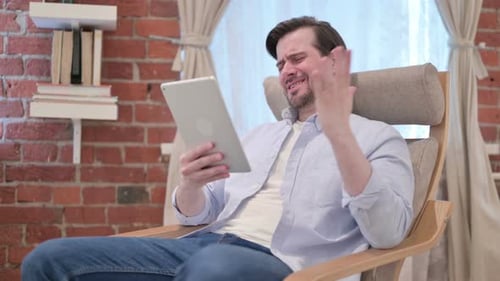 Man Frustrated Using Tablet in Chair