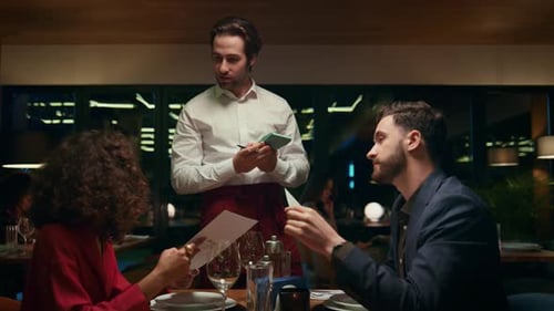 Handsome Waiter Helping Couple in Restaurant