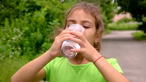 Child Drinks Water From Glass Outside
