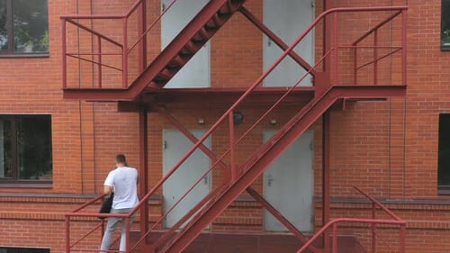 Man Walking Down Metal Stairs While Talking on Phone