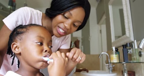 Mother Watches Child Brushing Teeth in Bathroom
