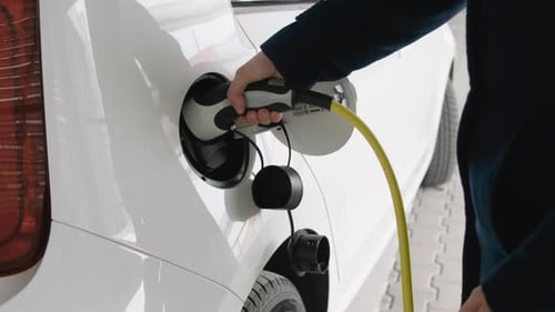 Woman Opening the Car and Disconnecting the Cable From an Electric Car