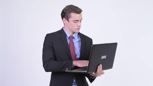 Young Adult Businessman Typing on Laptop, Smiling