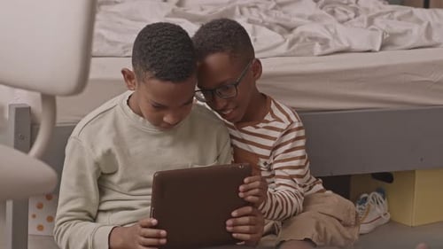 Two Happy Children Using a Tablet Together Indoors