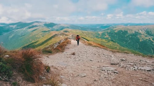 Tourist with a Backpack Climbing Up Along the Stone Mountain Trail on the Hill