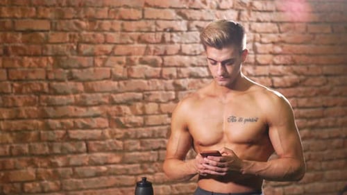 Athletic Man Drinking and Using Cell Phone