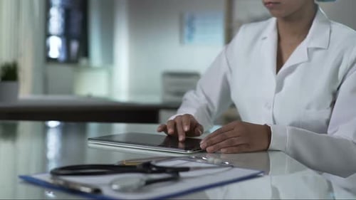 Female Doctor Scrolling Tablet Screen, Checking Patients Test Results, Clinic