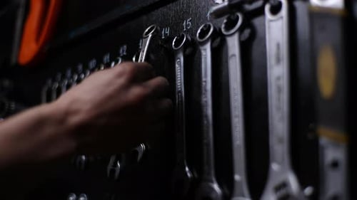 Nahaufnahme Hände eines unkenntlichen Handwerkers, der Schraubenschlüssel aus Instrumenten auswählt Set von Hängen an der Wand