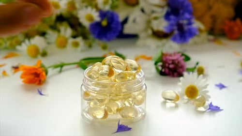 Golden Gel Capsules with Fresh Flowers and Hand