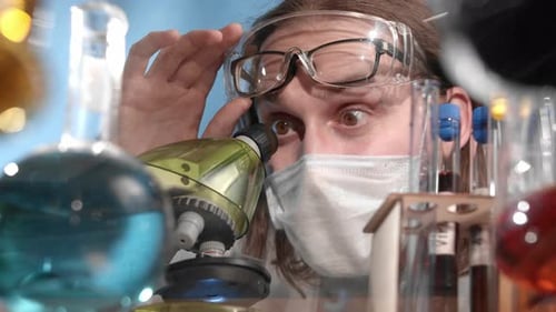 Scientist Analyzing Sample Through Microscope in Lab