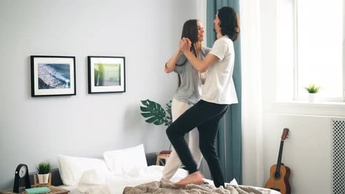 Happy Couple Dancing on Bed in Bedroom