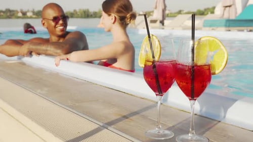 Young Couple Talking While Resting in the Swimming Pool Together