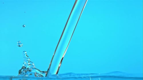 Clear Liquid Pouring into Water on Blue Background