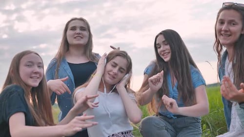Five Smiling Women Dancing and Singing Together Outdoors