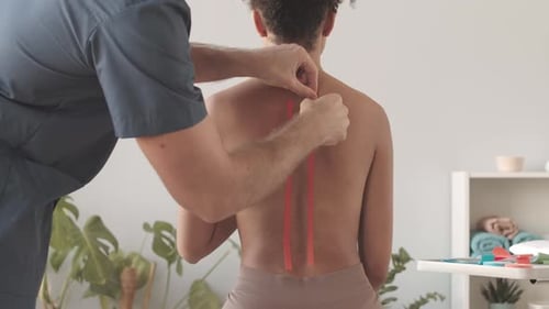 Doctor Applies Red Tape to Patient's Back