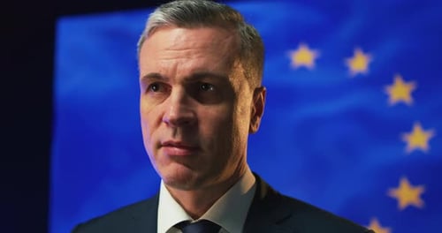 Man in Suit Speaking with EU Flag Backdrop