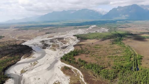 Drohne fliegt über den Sakukan River, Berge im Hintergrund
