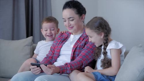 Mother and Children Enjoying Smartphone Content Together at Home