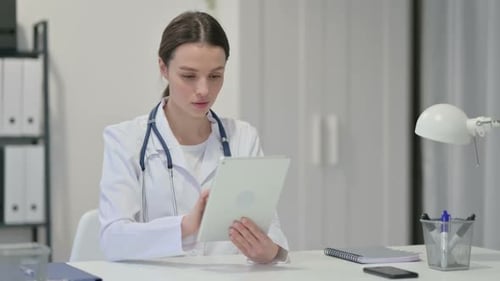 Young Woman Doctor Reviews Tablet in Office