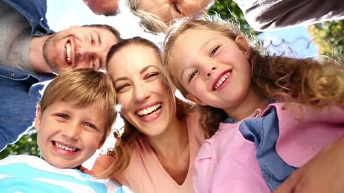 Família extensa em pé juntos no parque sorrindo para a câmera