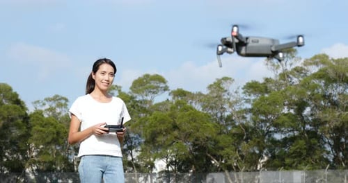 Frau kontrolliert fliegende Drohne