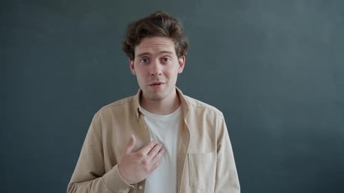 Zeitlupenporträt eines fröhlichen jungen Menschen, der auf sich selbst zeigt und Dankbarkeit ausdrückt